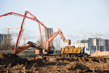Excavator load the sand to the heavy dump truck on construction site. Excavators and dozers digs the ground for the foundation and construction of a new building. Apartment renovation program
