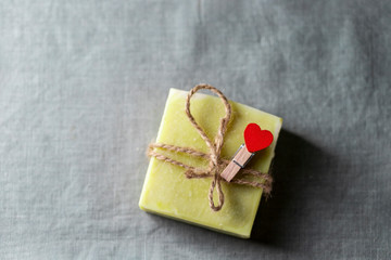 Natural handmade soap with a heart decor on a background of linen fabric.