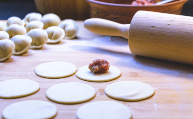 The process of making dumplings, dumplings or meat dumplings. Dumplings - Russian dumplings on a wooden background