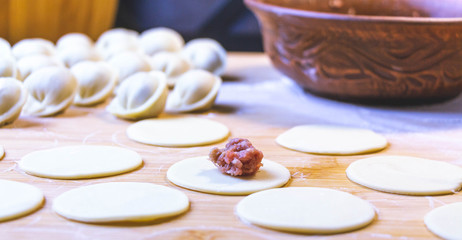 The process of making dumplings, dumplings or meat dumplings. Dumplings - Russian dumplings on a wooden background