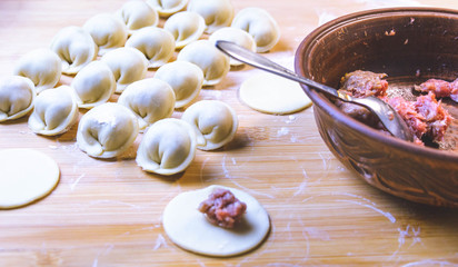 Raw dumplings - Russian dumplings on a cutting board and ingredients for homemade dumplings on a wooden table.