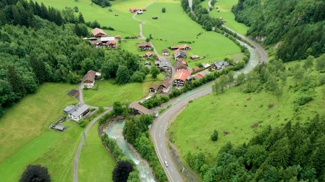Scenic Aerial View of Countryside in Mountains. Alpine Village with River and Car road. Agriculture and Ecotourism in Hinterstein, Germany. 4K Drone Fly over Shot