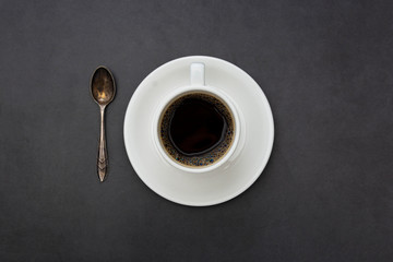 Coffee. White cup of coffee top view spoon and plate on dark background