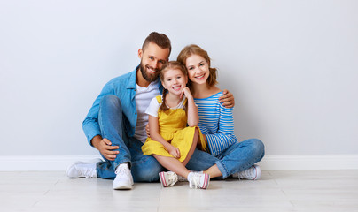 happy family mother father and child  near an empty brick wall.