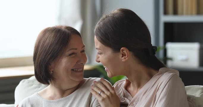 Affectionate mature mother and young daughter embracing looking at camera