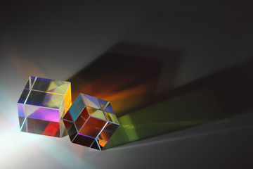 Two prisms of the cube are on the surface and cast long colored shadows