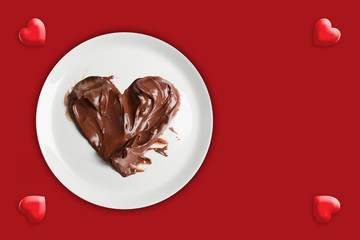 Chocolate heart in a plate on red background.