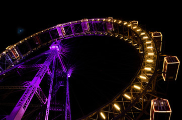 Night view of a Big Wheel lit with pink violet and golden lights