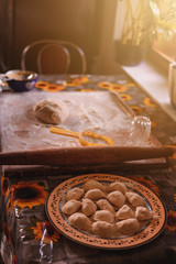 Cooking dumplings at home, dough and flour with dumplings on a wooden board.