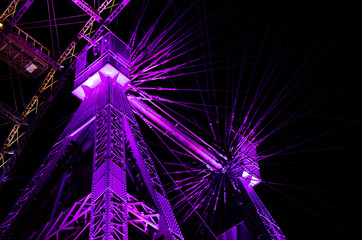 Night view of a Big Wheel lit with pink violet and golden lights