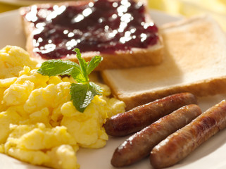 breakfast with scrambled eggs, sausage links and toast.
