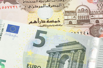 A blue and green, European five euro bank note with a five dirham bank note from the United Arab Emirates close up in macro