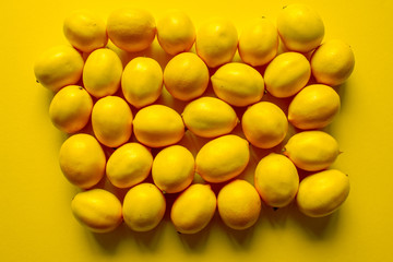 Top view many ripe lemons on a yellow surface, background or concept