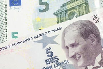 A close up image of a purple five Turkish lira bank note with a German five euro bill in macro