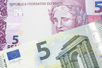 A five Euro bank note with a pink and purple five Brazilian reais bill.  Shot in macro.