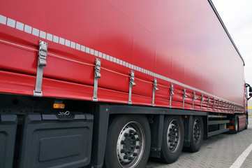Red tarpaulin covering the semi-trailer of the trucks. Truck transport.