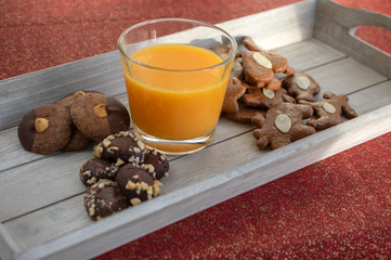 Group various kinds of delicious sweet Christmas cookies on light gray wood with fresh orange juice