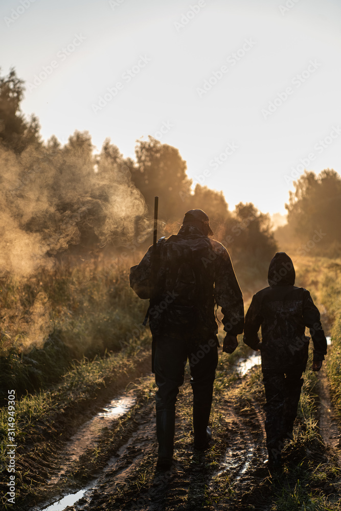 Wall mural summer hunting at sunrise. hunter moving with shotgun and looking for prey.