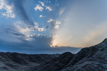 Obraz premium Scenic Sunset Sky with Strong Sunbeam and Cloudy Sky over Rocky Mountains Island