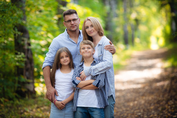 Fototapeta premium Happy family outdoors spending time together. Father, mother, daughter and son are having fun in a summer park at summer