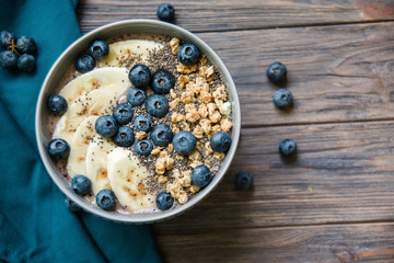 Healthy breakfast berry smoothie bowl topped with banana, granola, Blueberries and chia seeds with copy space