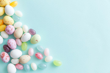 Happy Easter concept. Preparation for holiday. Easter candy chocolate eggs and jellybean sweets isolated on trendy pastel blue background. Simple minimalism flat lay top view copy space.