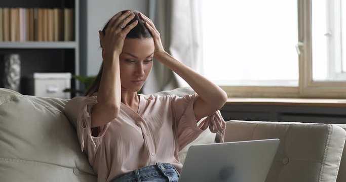 Angry upset young woman using laptop feel frustrated at home
