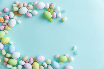Happy Easter concept. Preparation for holiday. Easter candy chocolate eggs and jellybean sweets isolated on trendy pastel blue background. Simple minimalism flat lay top view copy space.