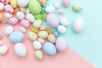 Happy Easter concept. Preparation for holiday. Easter candy chocolate eggs and jellybean sweets isolated on trendy pastel blue pink background. Simple minimalism flat lay top view copy space.