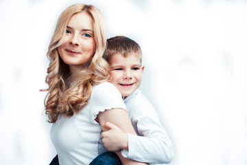 young modern blond curly mother with cute son together happy smiling family posing cheerful on white background, lifestyle people concept, sister and brother friends