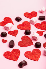 Valentine`s day poster with red hearts and chocolate candies on a pink background