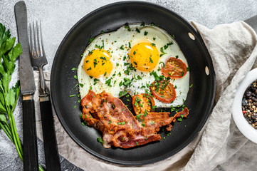 English breakfast - fried egg, tomatoes, bacon. Gray background. Top view