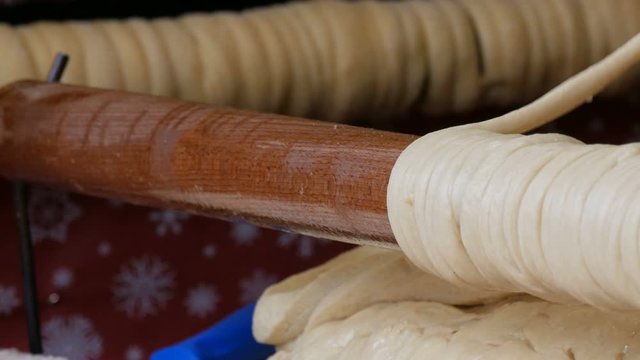 Female hands wrap the sticks of dough on a wooden stick. National Czech trdelnik sweet delicacy that is prepared on the street.Traditional Czech and Hungarian baking sweet bakery.