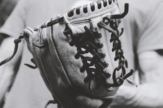 Vintage baseball photo with close up of old glove on ball player in black and white.
