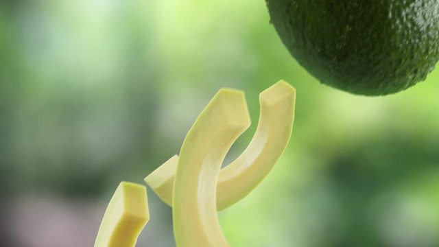 Avocado with Slices Falling on Garden Background