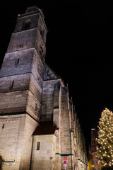 Fototapeta na wymiar Tall church tower and Christmas tree with lights. Taken in Dinkelsbüh, Germany at night.l