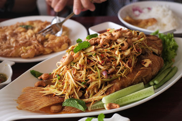 Fried fish covered with spicy salad and fried eggs