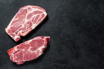 Raw pork steak on the bone. Grilled meat. Black background. Top view. Space for text
