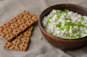 A glass bottle with kefir and kefir grains with bread rolls on the wooden table