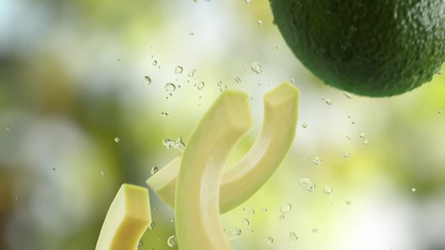 Avocado with Slices and Splash Falling on Garden Background