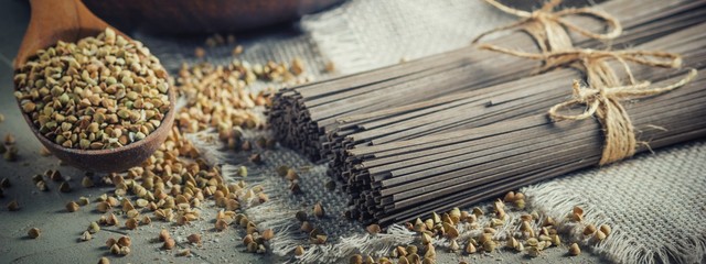 Rural still-life - traditional japanese soba noodles made of buckwheat flour and the peeled groats of buckwheat, on the background of burlap, closeup with selective focus - obrazy, fototapety, plakaty