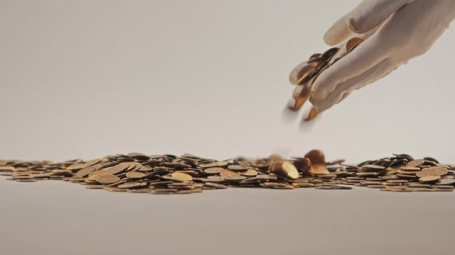 White-gloved hands scooping up a pile of gold coins. They sort out and scatter money.On white background. Garland. Money glitters.