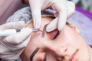 Cosmetic procedures for the treatment of eyebrows. Microblading in the beauty salon. Professional cosmetology. The process of applying the pigment.