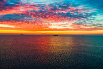 Sea sunrise over the waves and sailing ships