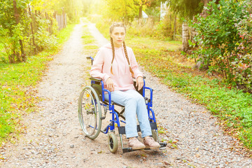 Young happy handicap woman in wheelchair on road in hospital park waiting for patient services....