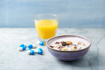 Bowl of granola with yogurt, nuts, raisins, cranberries and chia seeds. Sports supplements in background. Concept for a tasty and healthy meal. Stone - wooden background. 