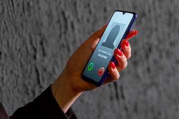 Phone call from unknown number. Scam, fraud or phishing with smartphone concept. Prank caller, scammer or stranger. Woman answering to incoming call. Hoax person with fake identity.