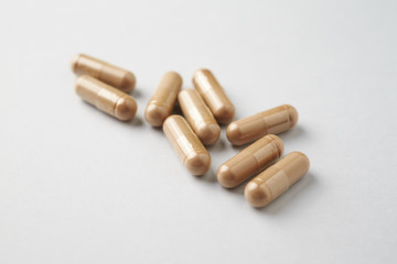 Reishi Mushroom capsules. Concept for a healthy dietary supplementation. Bright paper background. Close up. 