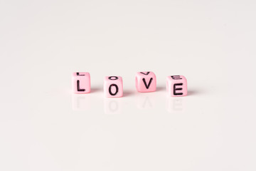 Love and Valentines Day concept: Miniature Couple with LOVE wordings on small beads on white backgrounds