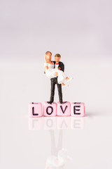 Love and Valentines Day concept: Miniature Couple with LOVE wordings on small beads on white backgrounds